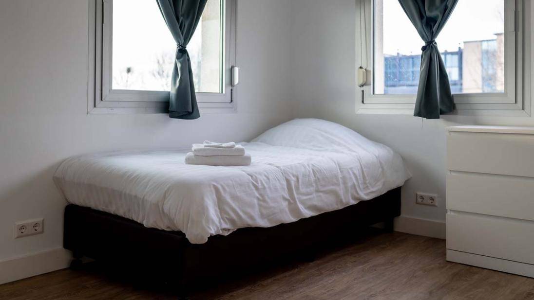 Kamer met bed en badlakens twee ramen op de achtergrond