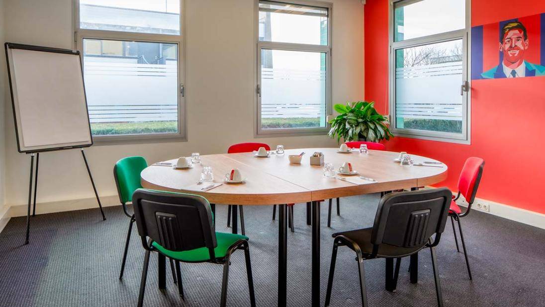 Vergaderruimte met kleine tafel stoelen flip-over en rode muur met schildering